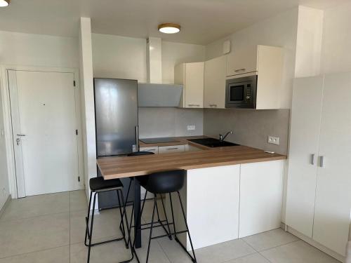 カンヌにあるSuper Apartment, Parking, Terrace, Lift, WIFI, Palm Beach, Cannesの白いキャビネットと木製のカウンタートップを備えたキッチン
