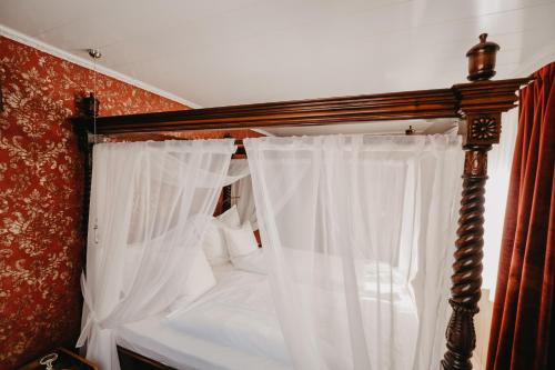 a bedroom with a canopy bed with white curtains at Altes Häusle am Waschbach Anno 1625 Ferienwohnungen und Doppelzimmer in Edenkoben