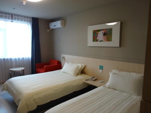 a hotel room with two beds and a red chair at Jinjiang Inn Wuhan Wuchang Railway Station in Wuhan