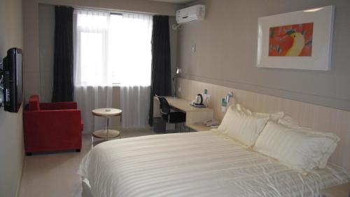 a bedroom with a bed and a desk and a window at Jinjiang Inn Wuhan Wuchang Railway Station in Wuhan