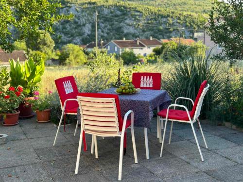 a table with four chairs and a table with fruit on it at STUDIO APARTMANI IZVOR in Blagaj