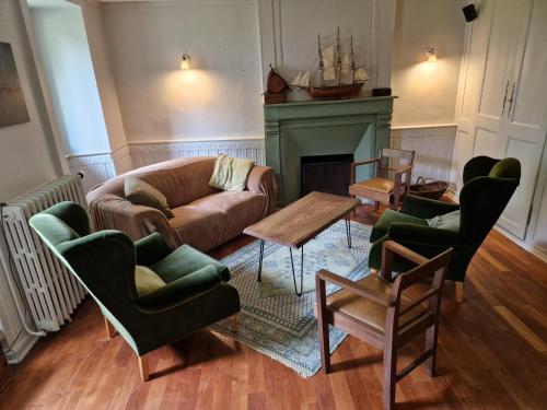 - un salon avec un canapé, des chaises et une cheminée dans l'établissement La Maison des Soeurs - Maison de charme du 18 ème siècle - Logement entier, à Trégomeur