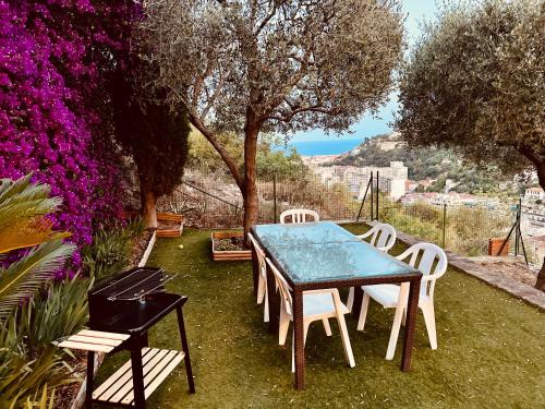 - une table et des chaises dans une cour fleurie dans l'établissement Nissa la bella, Piscine et vue mer, à Nice