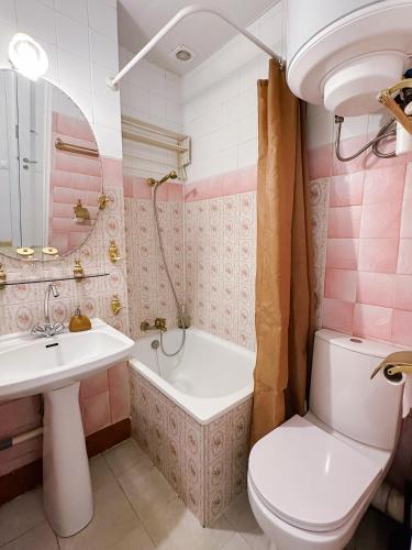 La salle de bains rose est pourvue d'un lavabo, d'une baignoire et de toilettes. dans l'établissement Paris center 2 rooms appt metro 14 Olympiades, à Paris