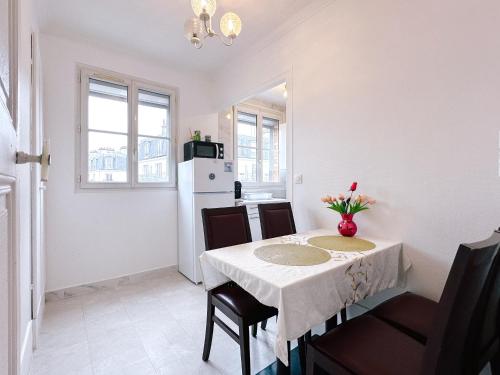- une cuisine blanche avec une table, des chaises et un réfrigérateur dans l'établissement Paris center 2 rooms appt metro 14 Olympiades, à Paris