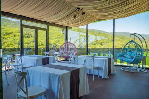 a room with tables and chairs with a view at Sabaduri Hills in Tsʼkhvarichamia