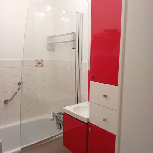 La salle de bains est pourvue d'une armoire rouge et d'une douche. dans l'établissement Appartement 100m de la plage et des commerces, à LʼIsle-Saint-Cast