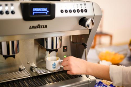 a person is making a cup of coffee in a espresso machine at Hotel Vico Alto Siena in Siena