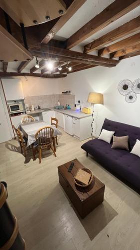 un salon avec un canapé violet et une table dans l'établissement Maisonnette calme, à Balleroy