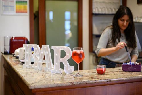 a woman standing at a bar with a glass of wine at Hotel Vico Alto Siena in Siena