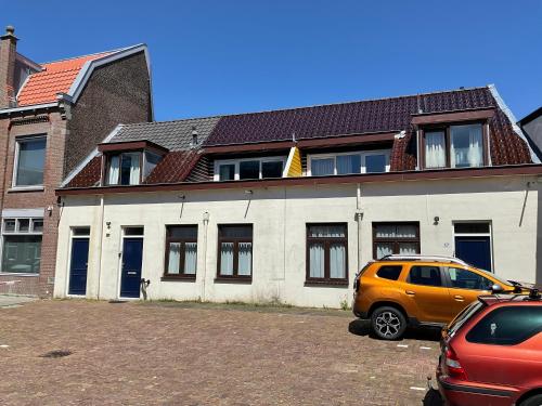 a yellow van parked in a parking lot in front of a building at Fisherman's House by Hofstad Hotels in Scheveningen
