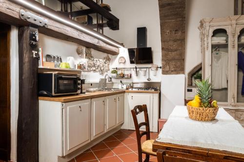 a kitchen with white cabinets and a table with a bowl of fruit at Angoletto Medioevale in Viterbo