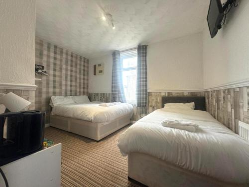 a bedroom with two beds and a tv in it at Tower Central hotel Albert Road in Blackpool