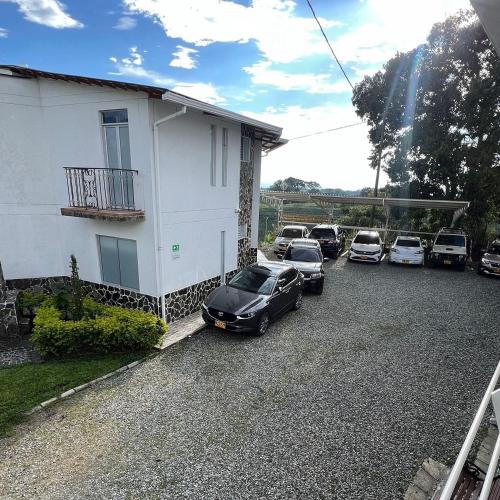 a group of cars parked in a parking lot next to a house at Castillo Del Toro in Armenia