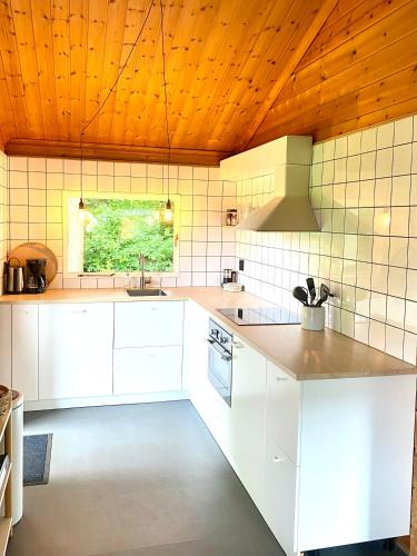 a kitchen with white cabinets and a wooden ceiling at Hip Huisje van Hout in Gramsbergen