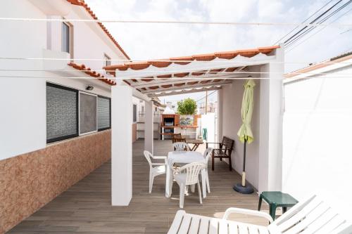 a patio with white chairs and a white table and chairs at Nazare with Garden and Barbecue in Nazaré