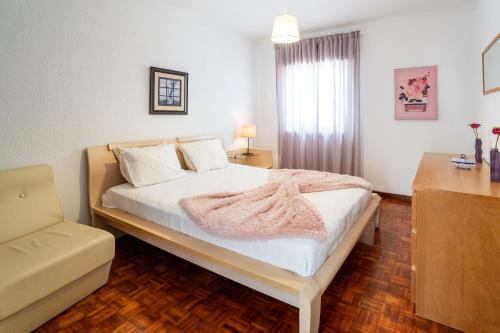 a bedroom with a bed with white sheets and a window at Nazare with Garden and Barbecue in Nazaré
