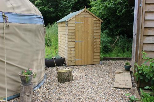 a small wooden shed in a yard with a garden at The Yurt at Worcesters Farm in Canterbury