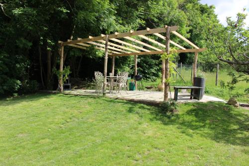 a wooden pergola with a table and a bench at The Yurt at Worcesters Farm in Canterbury