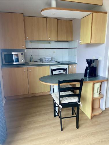 une cuisine avec une table et une chaise dans une pièce dans l'établissement La Rochelle Minimes - Studio meublé avec piscine, à La Rochelle