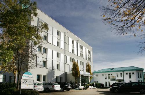 a white building with cars parked in a parking lot at ateckhotel Kirchheim/Teck in Kirchheim unter Teck