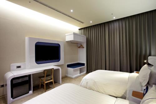 a hotel room with two beds and a flat screen tv at Airline Inn Green Park Way in Taichung