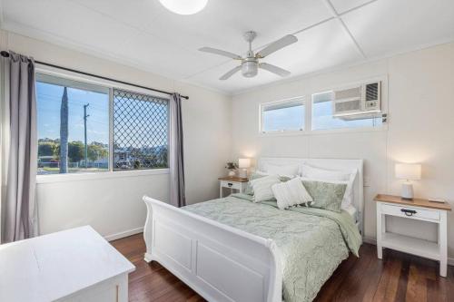 una camera da letto bianca con un letto e una finestra di Warm and Cozy Cottage House a Gympie