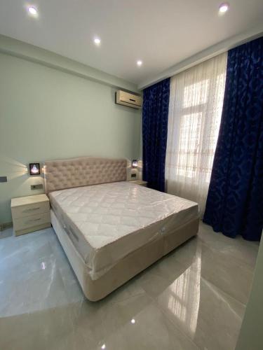 a bedroom with a large bed and blue curtains at Buzovna Delmar Luxury Residence in Mardakan