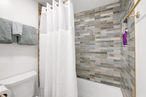 a bathroom with a white shower curtain and a brick wall at Heavenly Lakeside Retreat Close to downtown in South Lake Tahoe