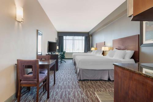 a hotel room with two beds and a desk at Best Western Plus Brandon Inn in Brandon