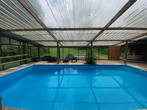 une piscine sous une pergola avec une piscine bleue dans l'établissement La Demeure du Domaine de Tertu - 12 pers, à Villedieu-lès-Bailleul