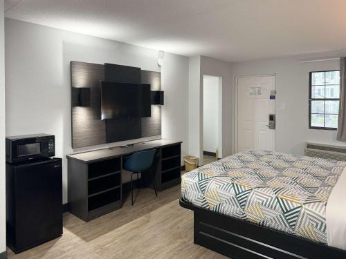 a bedroom with a bed and a desk with a television at Motel 6 Huntsville AL University Dr. in Huntsville