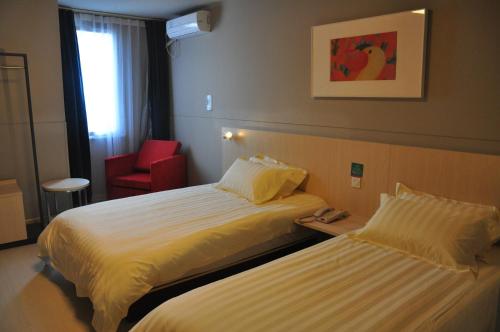 Cette chambre d'hôtel comprend deux lits et un fauteuil rouge. dans l'établissement Jinjiang Inn Xiaoshan International Airport, à Xiaoshan