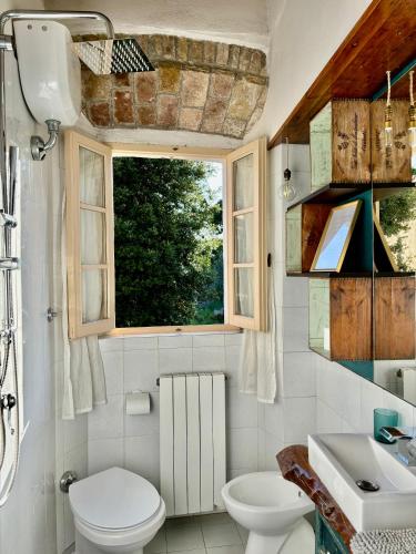 a bathroom with a toilet and a sink and a window at L'Antica Nicchia - Centro Storico in San Gimignano