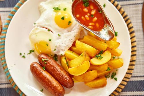 a plate of food with eggs sausage and fruit at Igwara Lodge in Kamdini