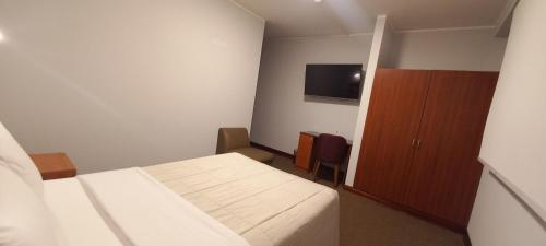 a room with a bed and a cabinet and a tv at HOTEL Javier Prado Inn in Lima