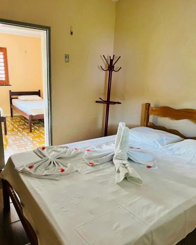 a bed with white sheets and a cross on the wall at Complexo Turístico Gruta da Serra in Guaramiranga