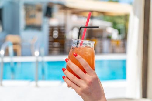a woman with red nail polish holding a drink at Sandy Beach Complex - Poolside Studios & Seaside Apartments in Kavos