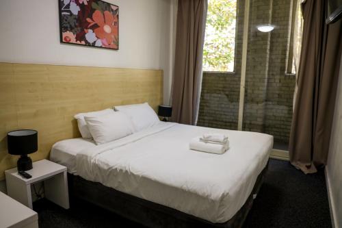 a hotel room with a bed and a window at Nomads Sydney in Sydney