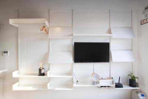 a white wall with white shelves and a tv at Baguni Hostel in Suncheon
