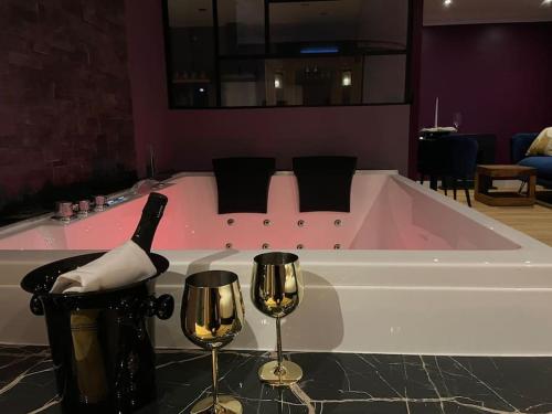 a bath tub with a bottle of wine and two wine glasses at Le Cocon des Granges - Suite Sauna Jaccuzi SPA in Bonnières-sur-Seine