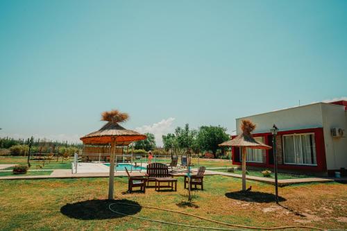 un groupe de tables et de chaises sous des parasols près d'une piscine dans l'établissement Cabañas Alma de Diamante, à San Rafael