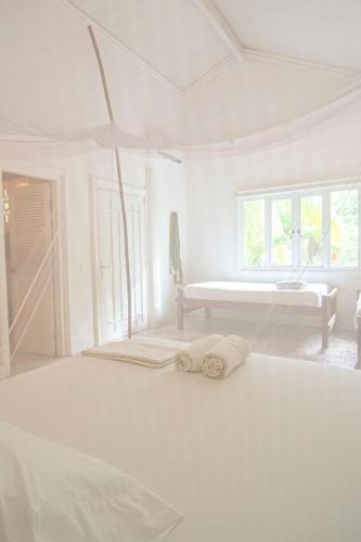 a white bedroom with a bed with towels on it at Hostal Secreto in Isla Grande