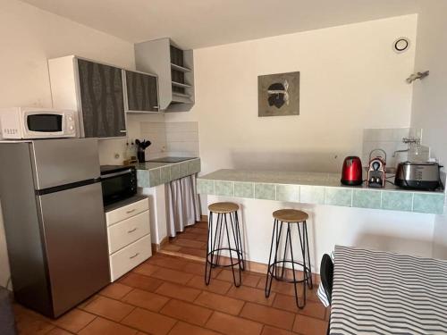 La cuisine est équipée d'un réfrigérateur et de deux tabourets de bar. dans l'établissement Rez de villa bordure Ajaccio, à Ajaccio