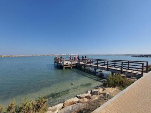 a pier in the water with people standing on it at CHALET A 5 METROS DEL MAR.Wifi gratis in Murcia