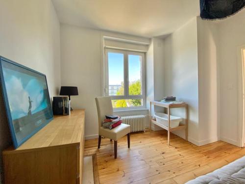 un salon avec une grande télévision et une chaise dans l'établissement LA MAISON DU STEIR - Villa Jardin en centre ville, à Quimper