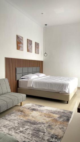 a white bedroom with a bed and a couch at Eben Haezer Villas in Karangploso