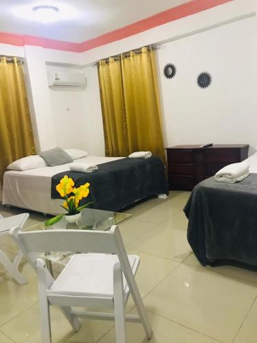 a bedroom with two beds and a table with a vase of flowers at Hotel Dubaird in Santo Domingo