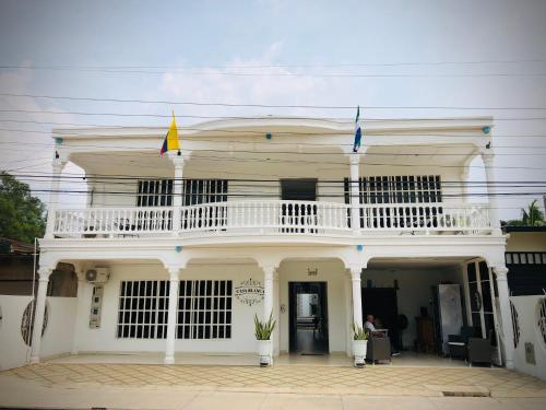 a white building with a balcony on top of it at Casa Blanca Guaviare Hostel in San José del Guaviare