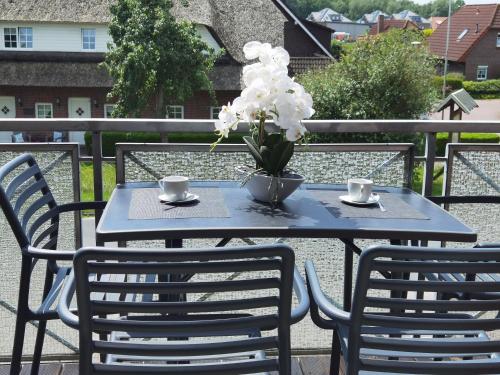 a blue table with two chairs and a vase with white flowers at Schaake Hooksiel - Charmante Reetdachwohnung & Kostenfreier Parkplatz in Hooksiel